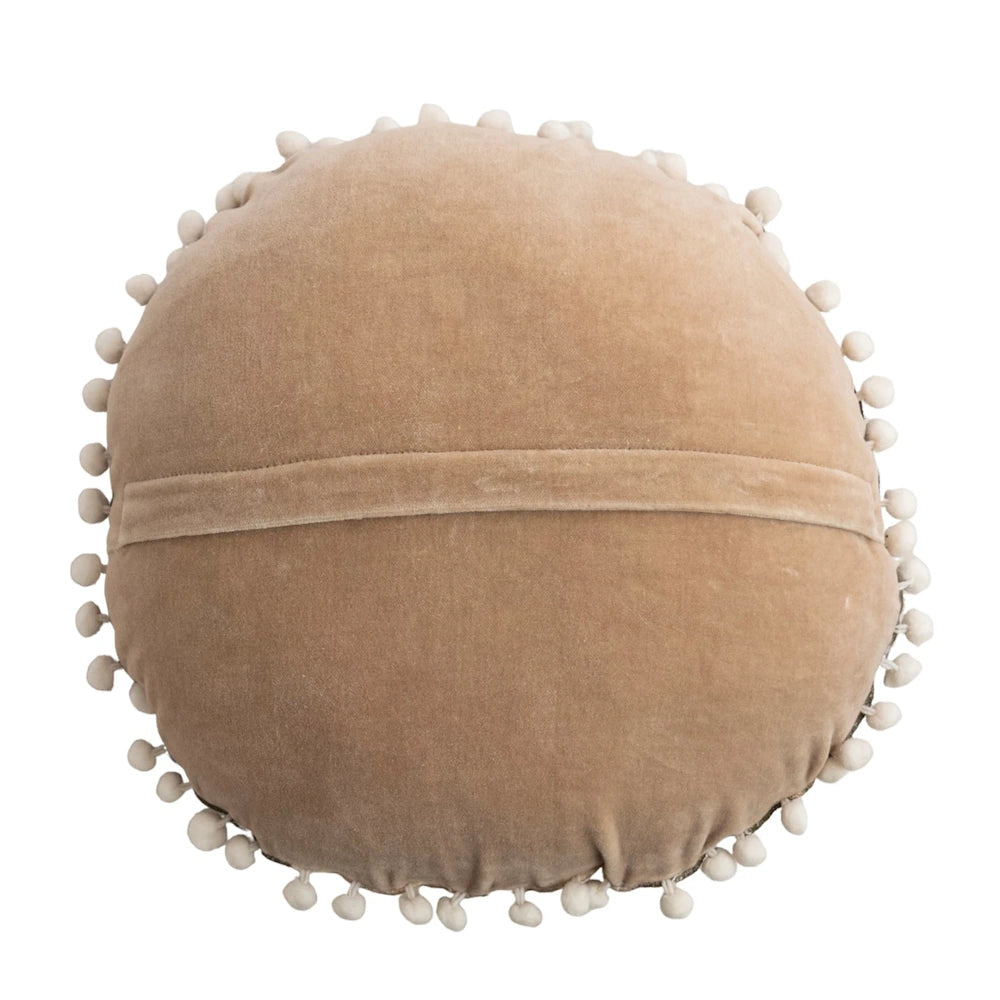 Back view of a round beige velvet pillow with a center flap enclosure and cream pom-pom edging.
