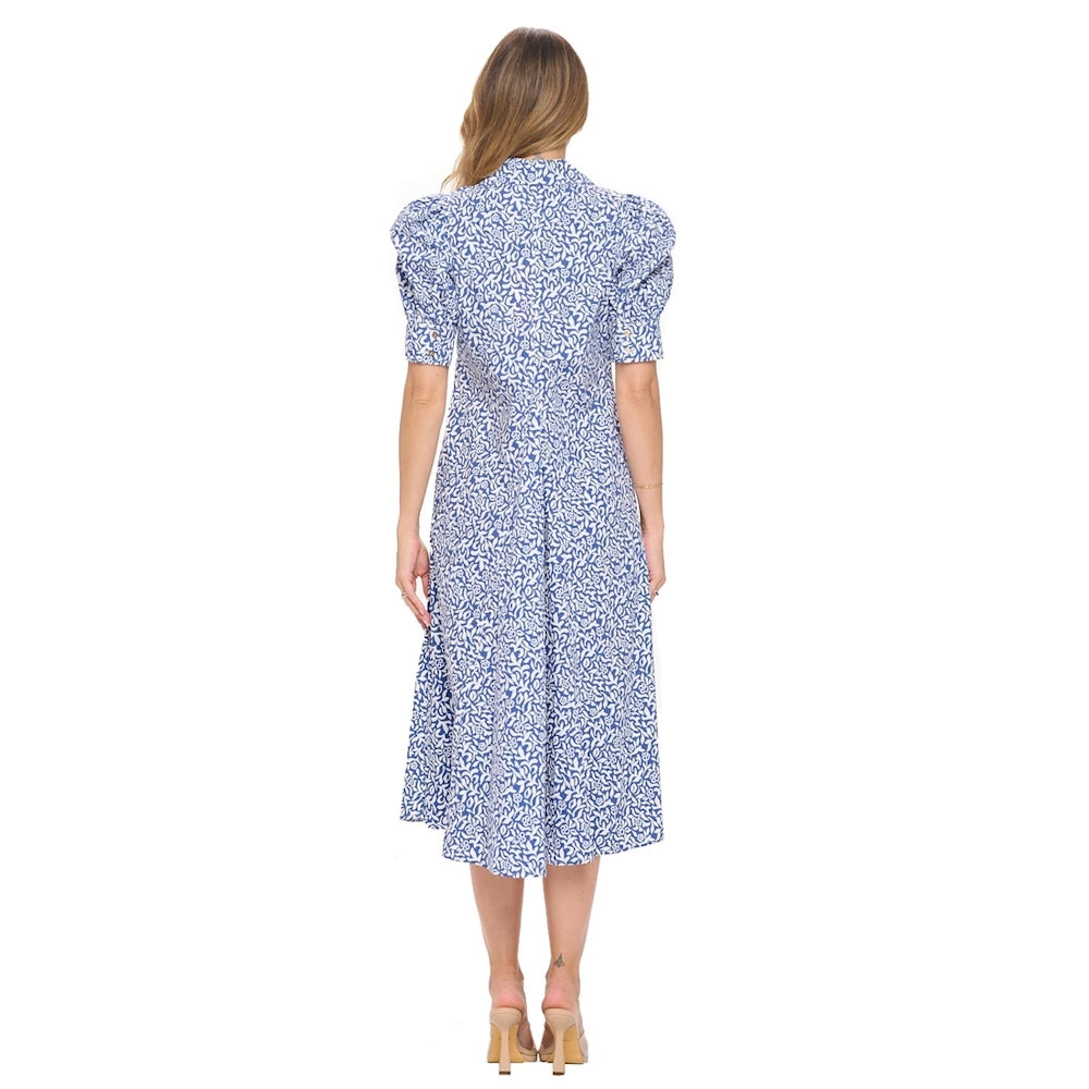 Back view of a woman wearing a blue and white floral bubble-sleeve pleated midi dress with tan heeled sandals.