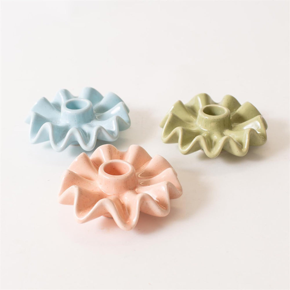 Three ceramic ruffle-rimmed taper candle holders in pastel pink, light blue, and sage green.