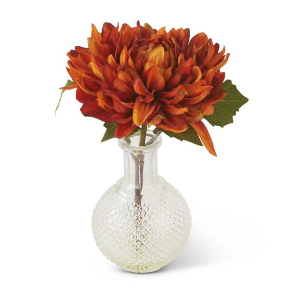 Rust orange artificial mum bloom in a textured clear glass vase with faux water.