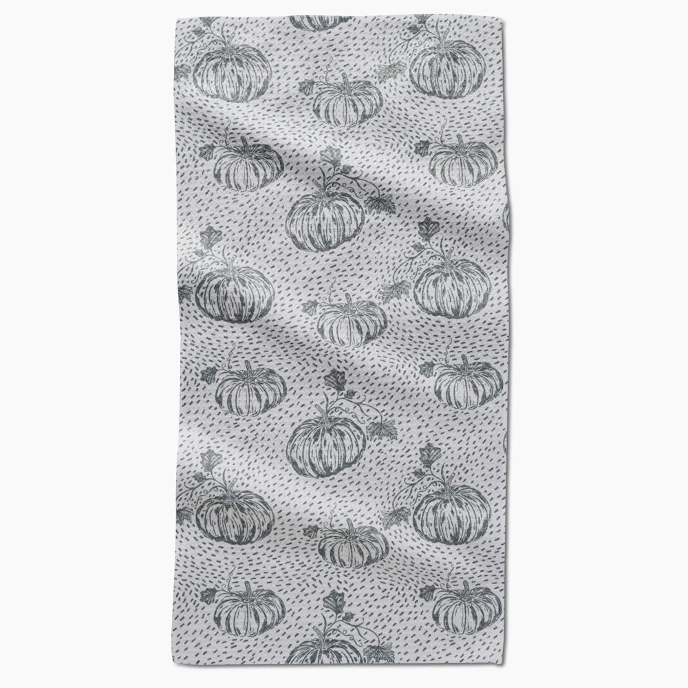 A light gray kitchen towel featuring a repeating pattern of sketched sage green pumpkins and speckles.
