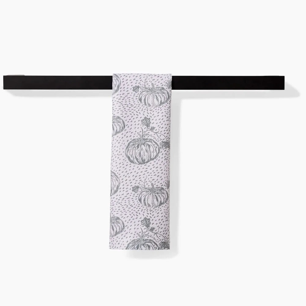 White kitchen towel with gray pumpkin sketches hanging over a black bar.