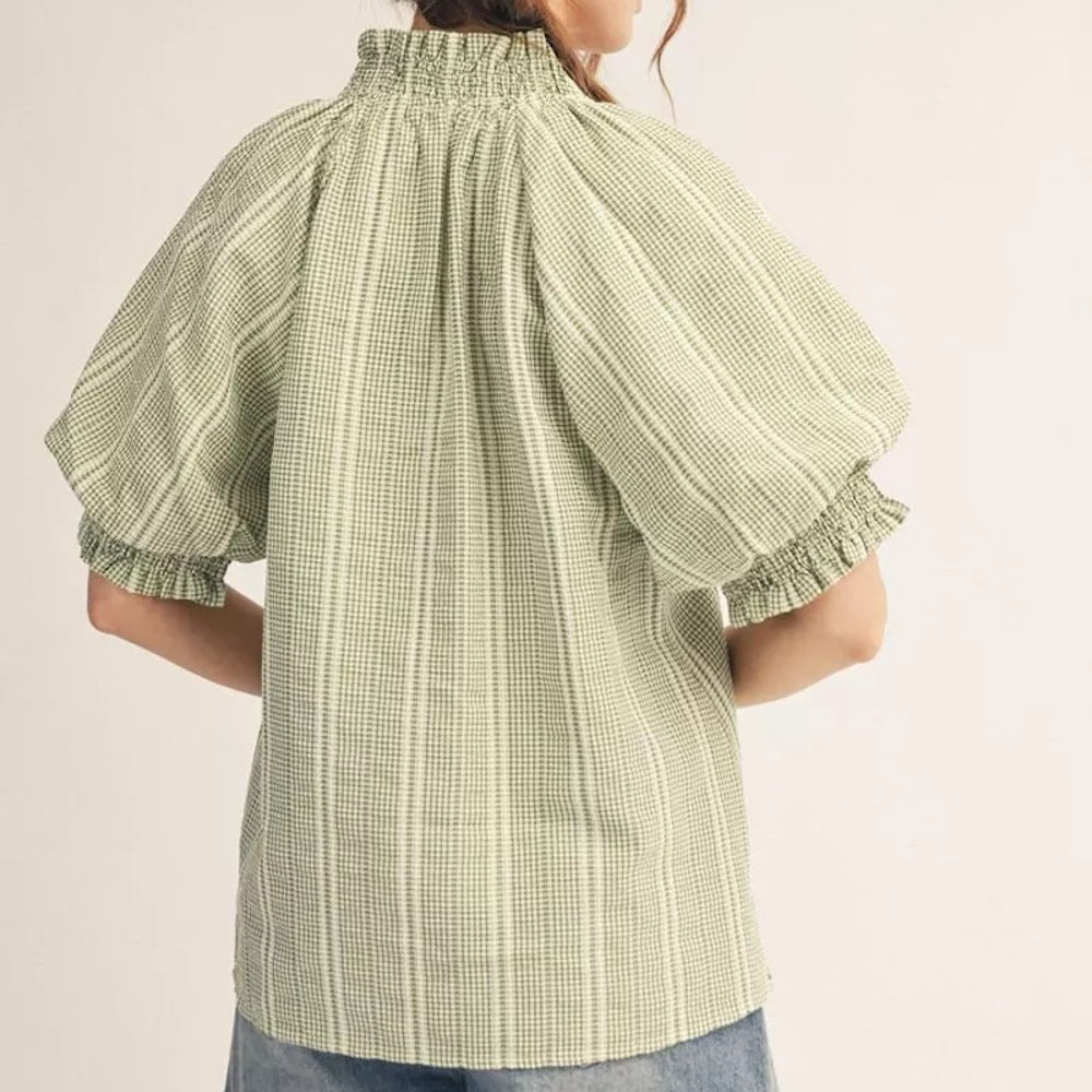 Back view of a person wearing a green and white gingham blouse with puff sleeves and a high smocked neckline.