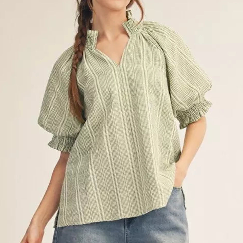 Green and white striped blouse with puff sleeves, a ruffled collar, and V-neckline worn with blue jeans.