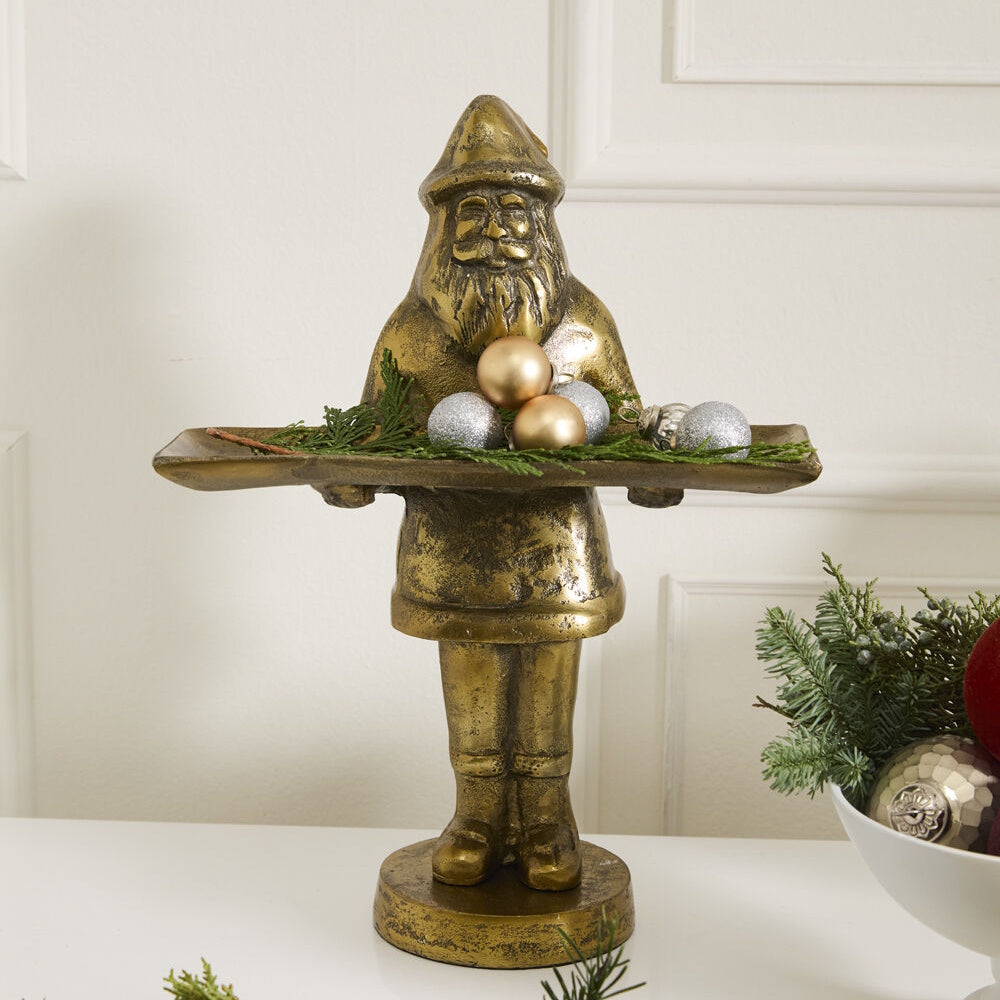 Front view of the antique gold Saint Nick dish stand holding a tray decorated with holiday ornaments and greenery.
