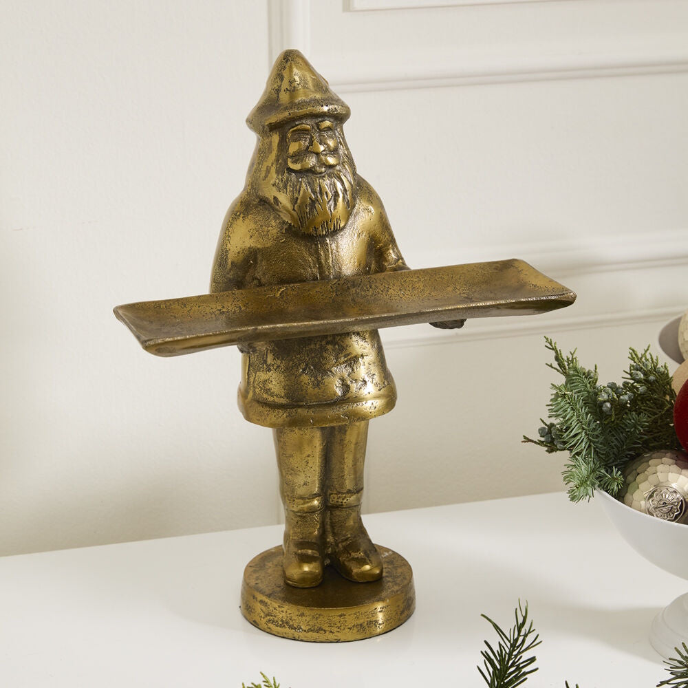Front view of the antique gold Saint Nick dish stand styled on a white tabletop with holiday greenery.