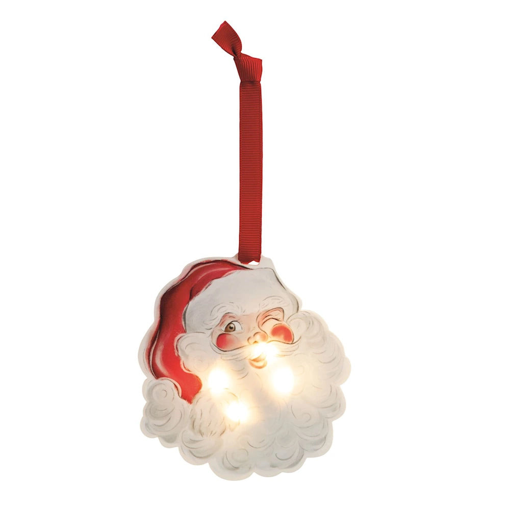 Illuminated winking Santa Claus acrylic ornament hanging from a red ribbon.