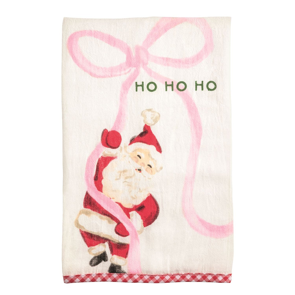 White towel featuring an illustration of Santa hanging from a large pink bow with green "HO HO HO" text.
