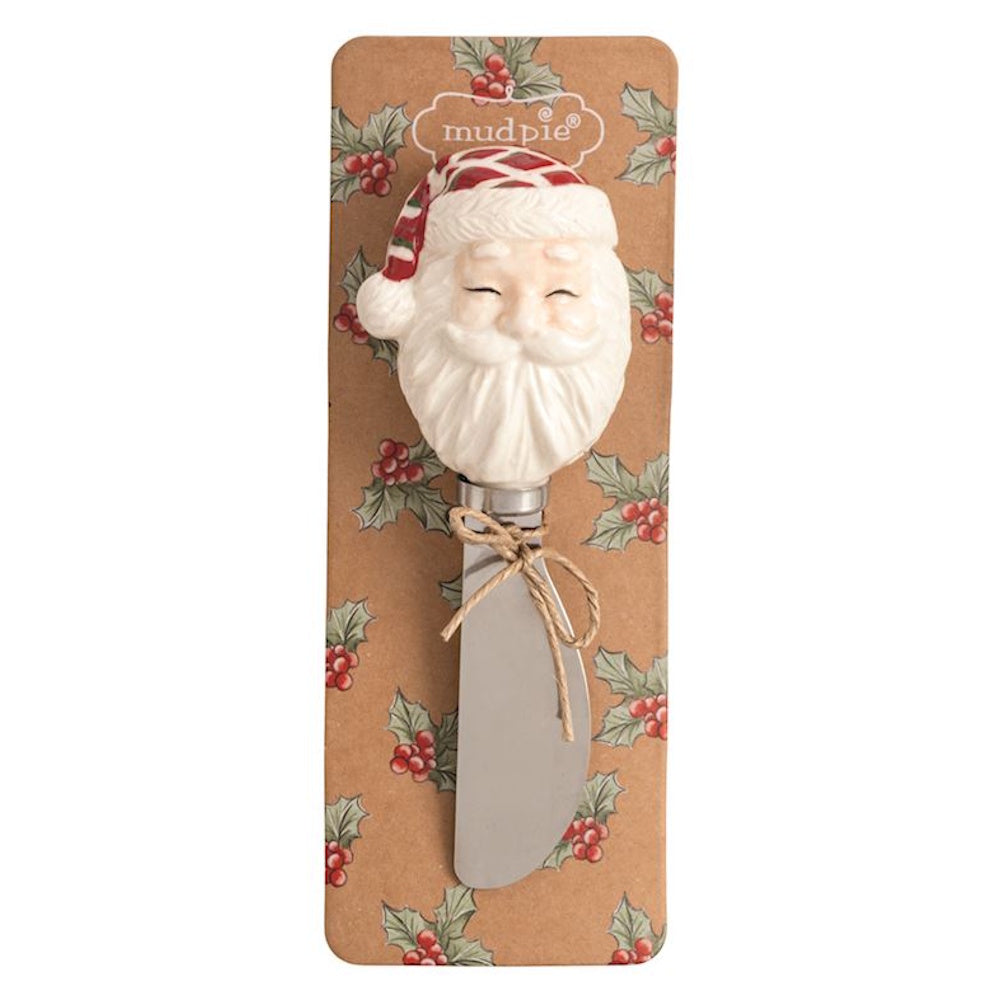 Cheese spreader with a ceramic Santa Claus head handle on a holly-patterned backing card.