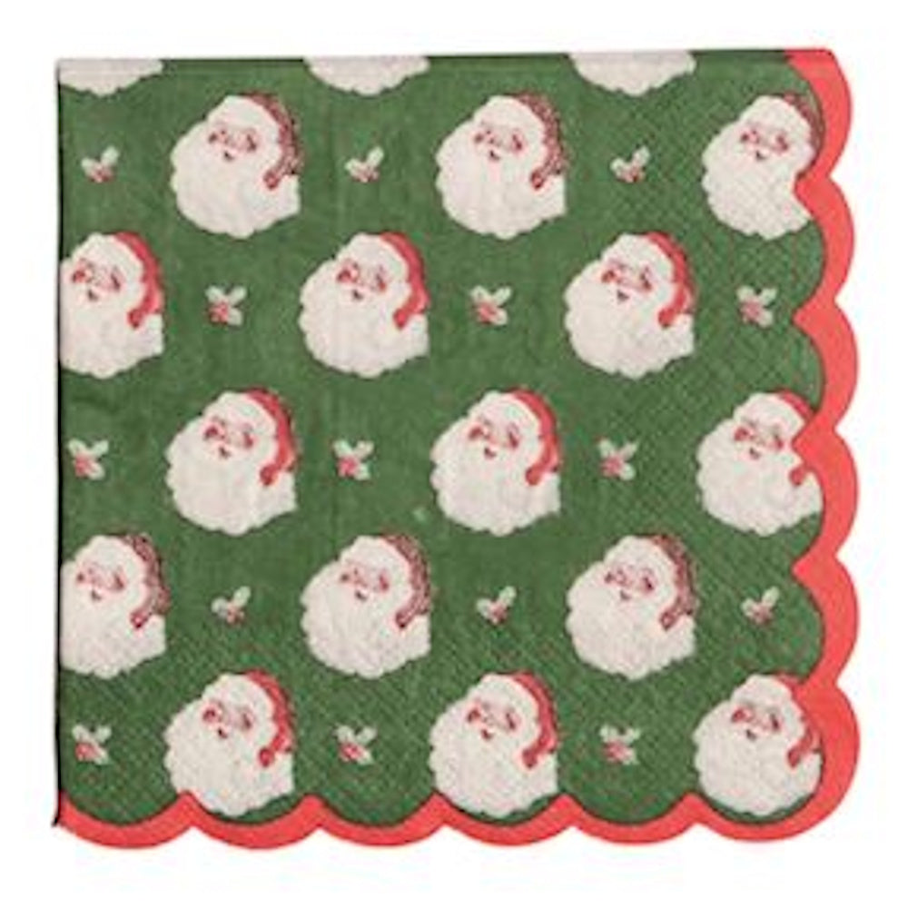 Green cocktail napkin with a repeated vintage Santa Claus head pattern and red scalloped edges.