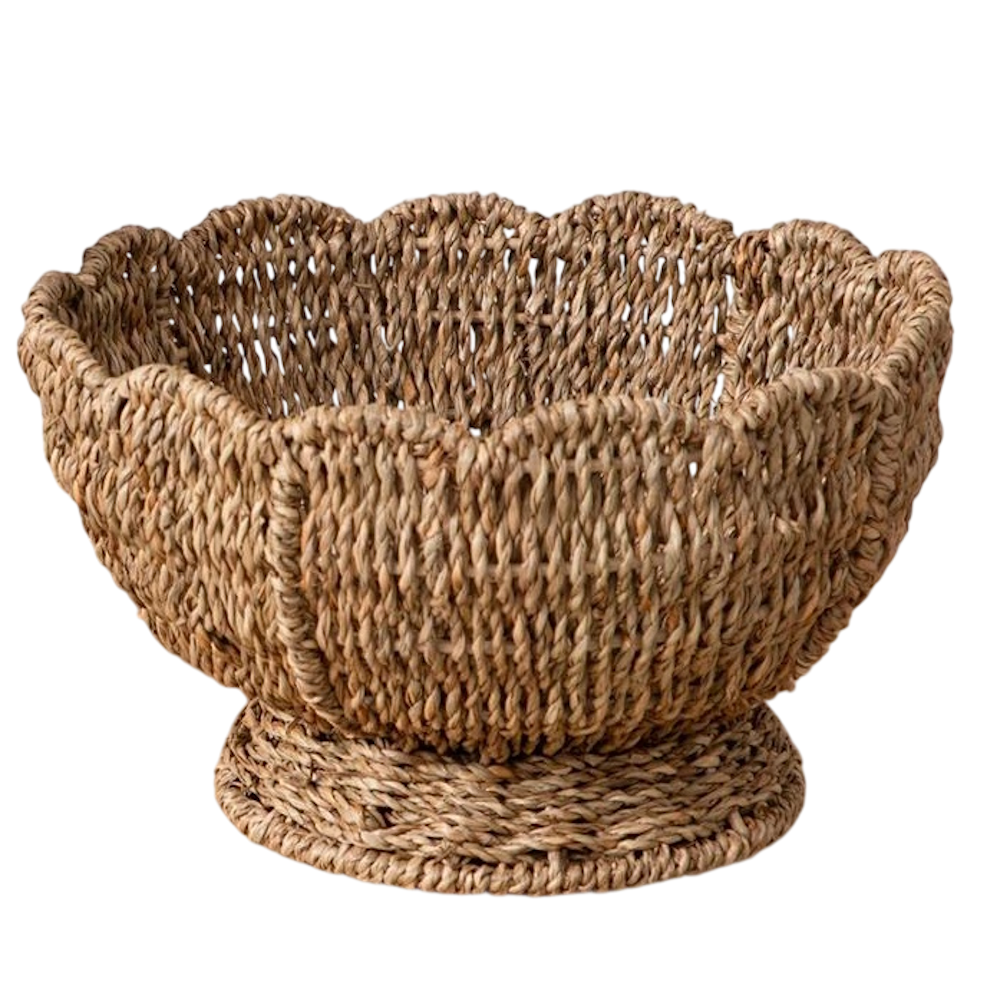 Round woven wicker bowl with a scalloped rim and a pedestal base on a white background.