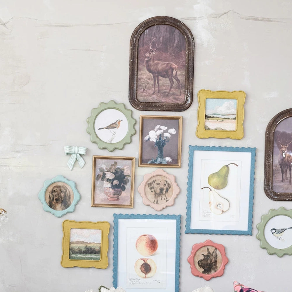 Shabby chic gallery wall decor with pastel scalloped picture frames, bird illustrations, and rustic deer portraits.