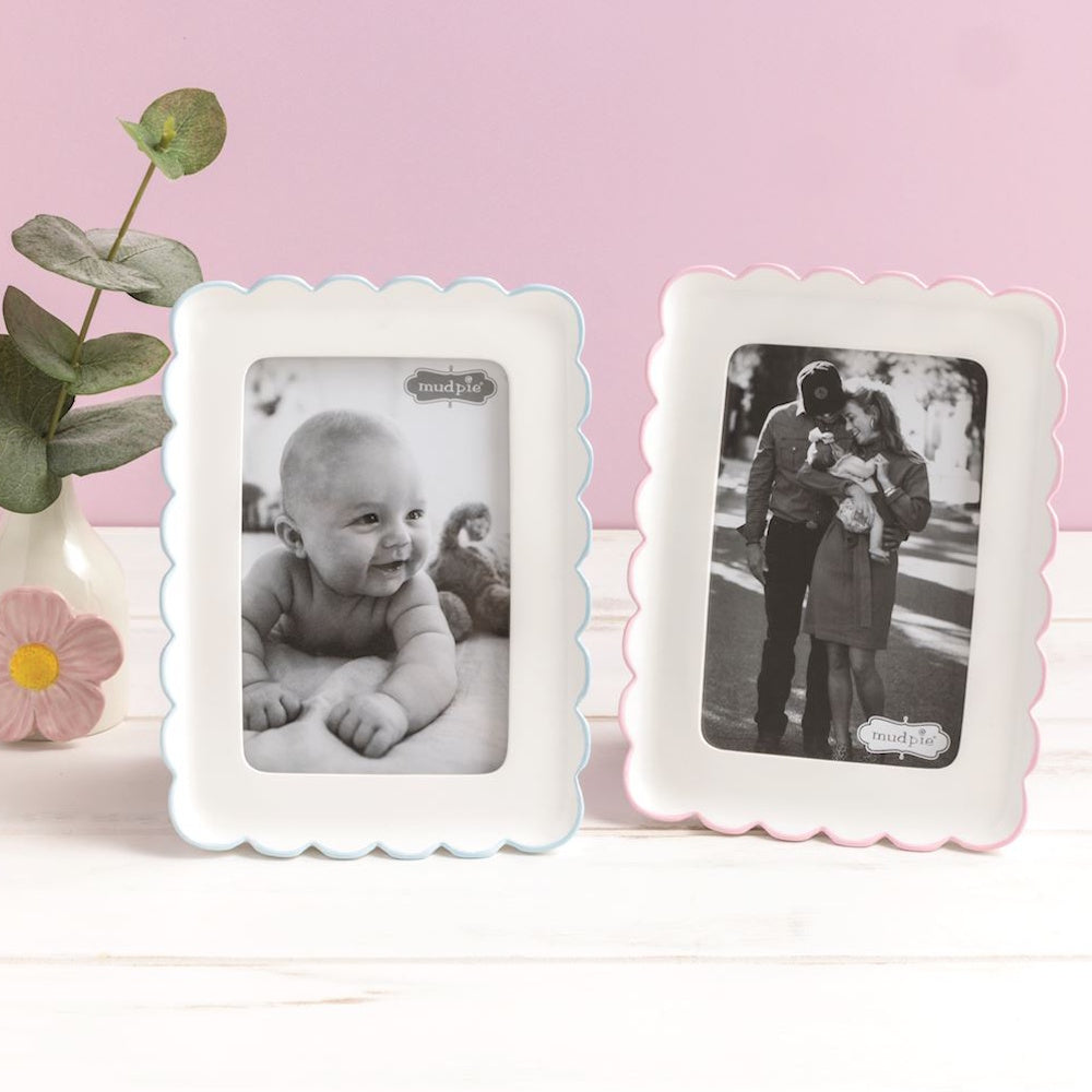 Two Mud Pie white scalloped resin frames with blue and pink borders, displaying black and white baby photos.