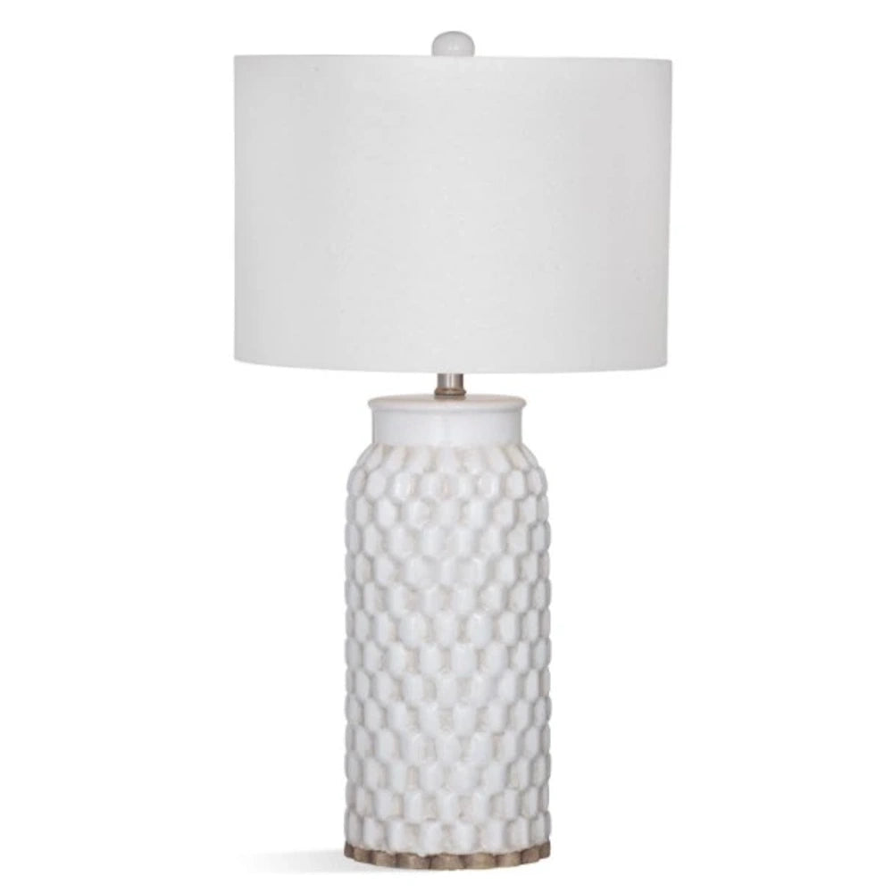 White table lamp with a textured, honeycomb ceramic base and a white drum lampshade.