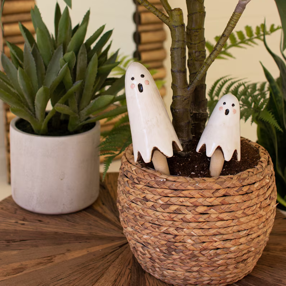 Two ceramic ghost plant sticks in a woven potted plant basket, Halloween garden decor.