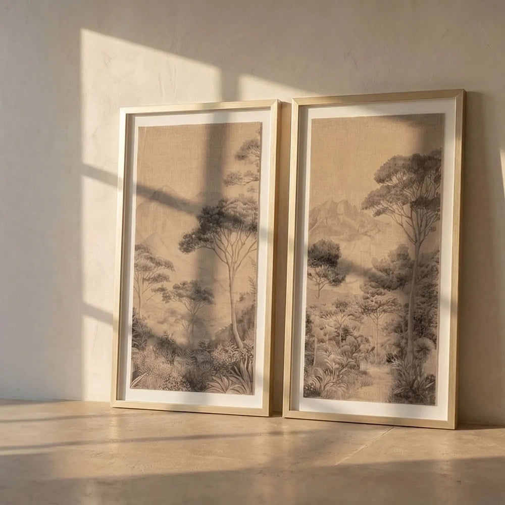 Set of two framed landscape wall art panels leaning against a wall, bathed in warm sunlight.