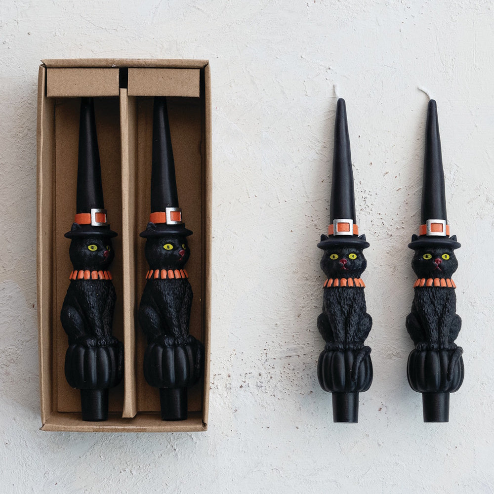 Set of black cat taper candles wearing witch hats, shown in box and standing.