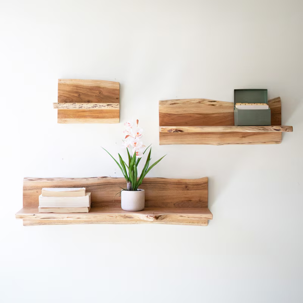 Three natural live-edge wooden shelves in varying sizes mounted against a plain white wall.