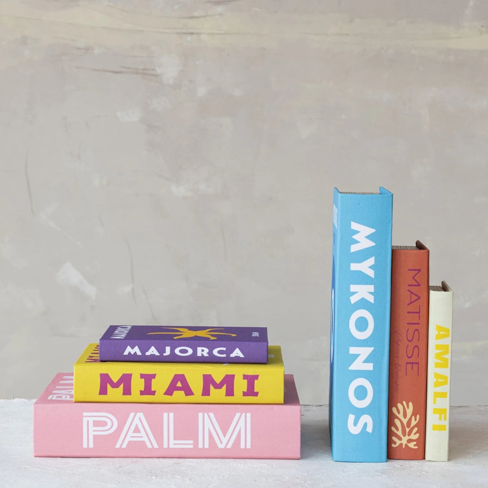 Stack of vibrant decorative travel books: Majorca, Miami, Palm, Mykonos, Matisse, and Amalfi for home shelf styling.