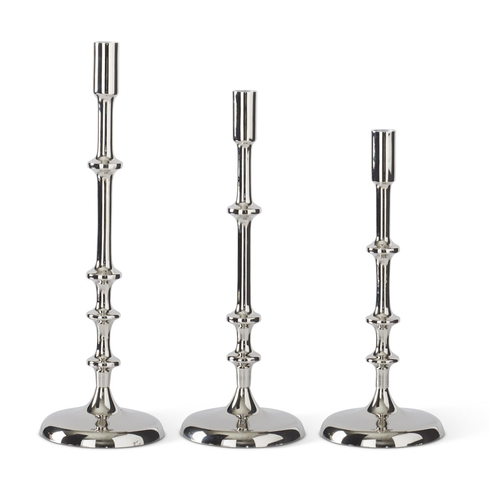 Set of three silver metal taper candle holders with ribbed stems in graduated heights and polished finish.