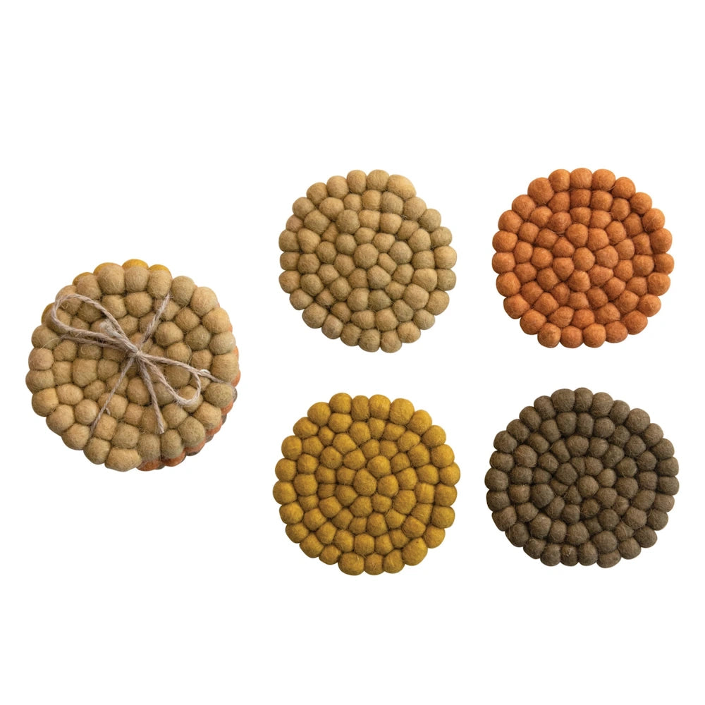 Set of 4 round felt ball coasters in earth tones with a tied stack on a white background.