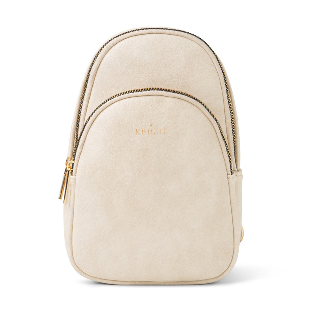 Cream-colored Kedzie mini backpack sling bag with zippered compartments against a white background.