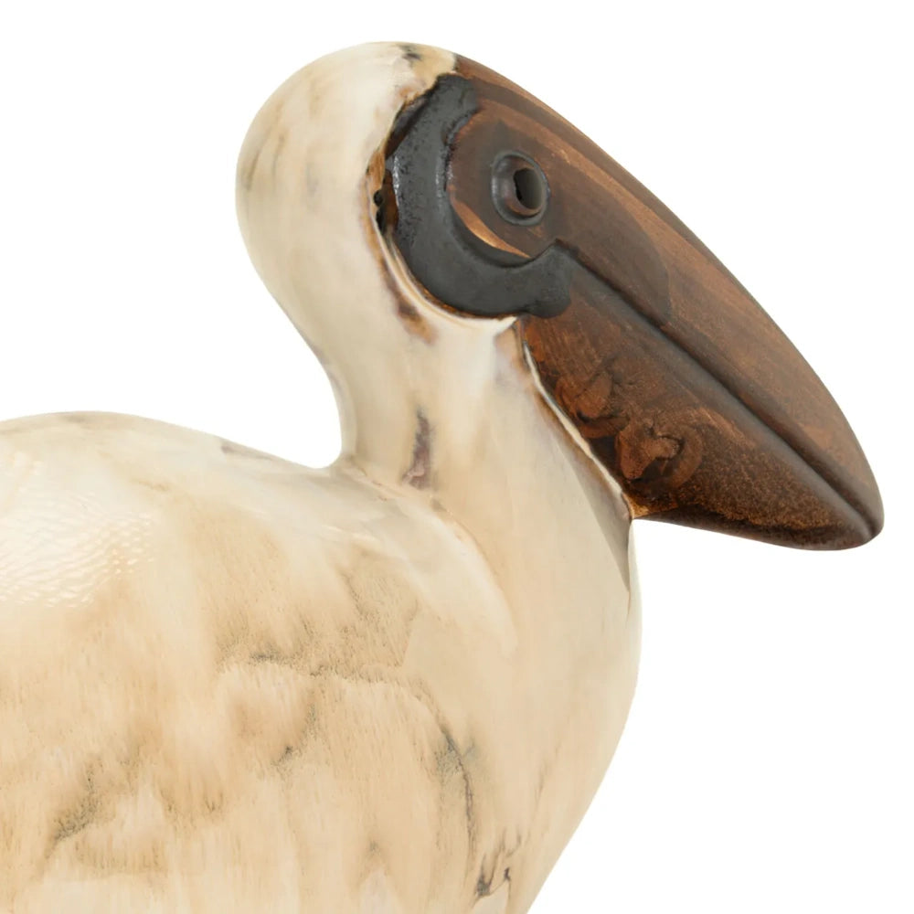 Close-up of a smooth, cream-colored pelican sculpture with a polished dark wood beak.