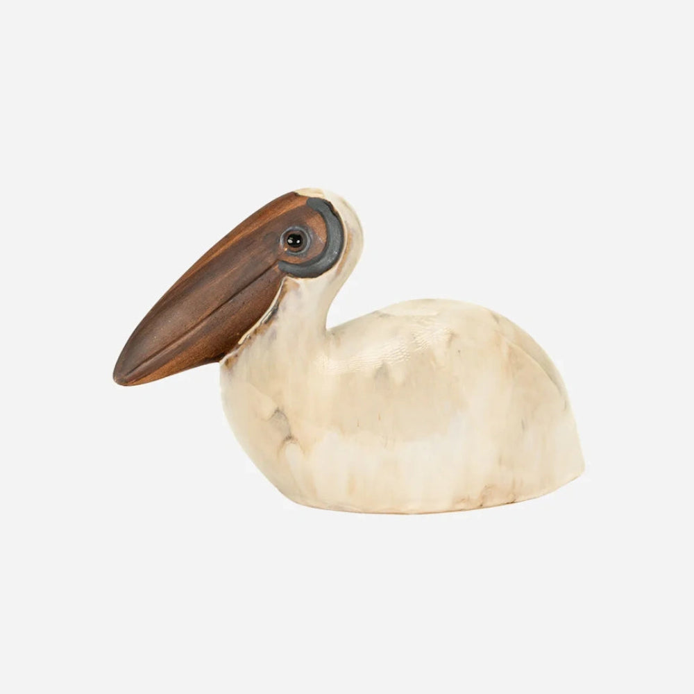 Ceramic pelican figurine with an off-white body and a large brown beak on a plain white background.