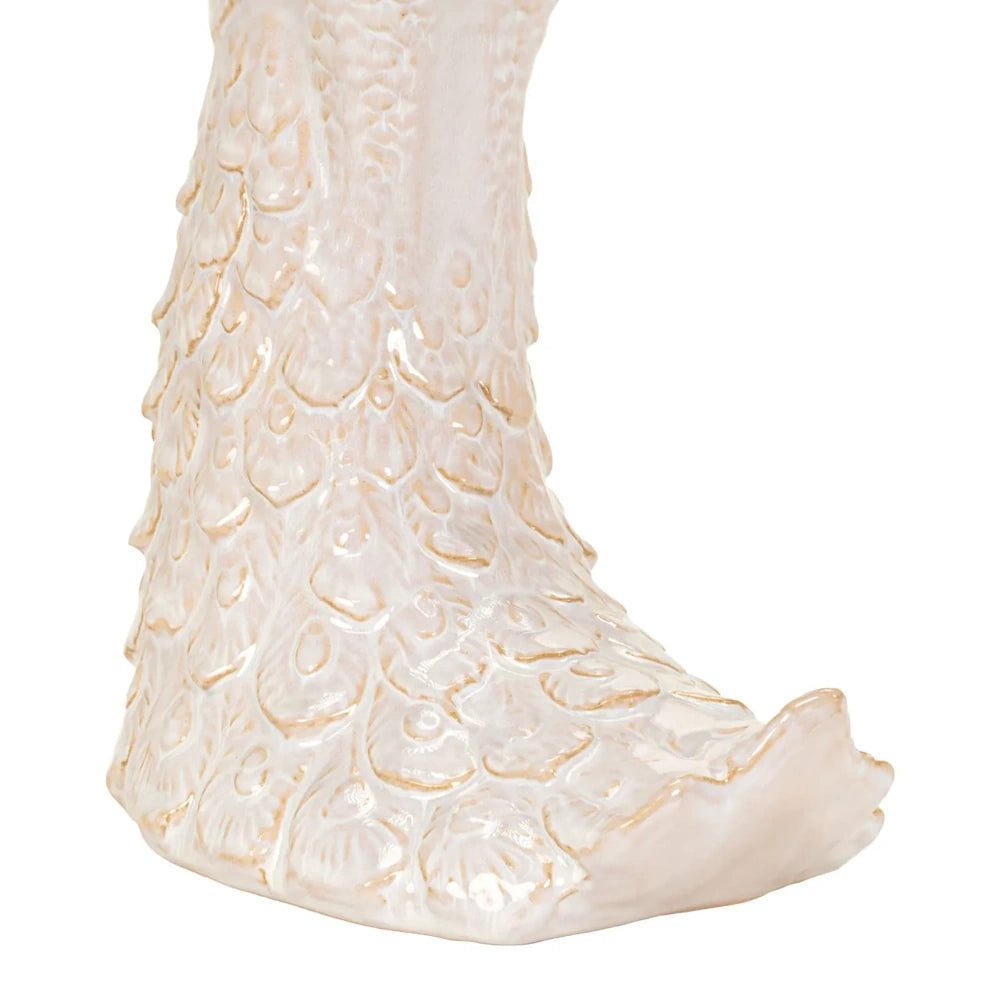 Close-up of the base of a cream ceramic bird sculpture showing detailed textured feather patterns.