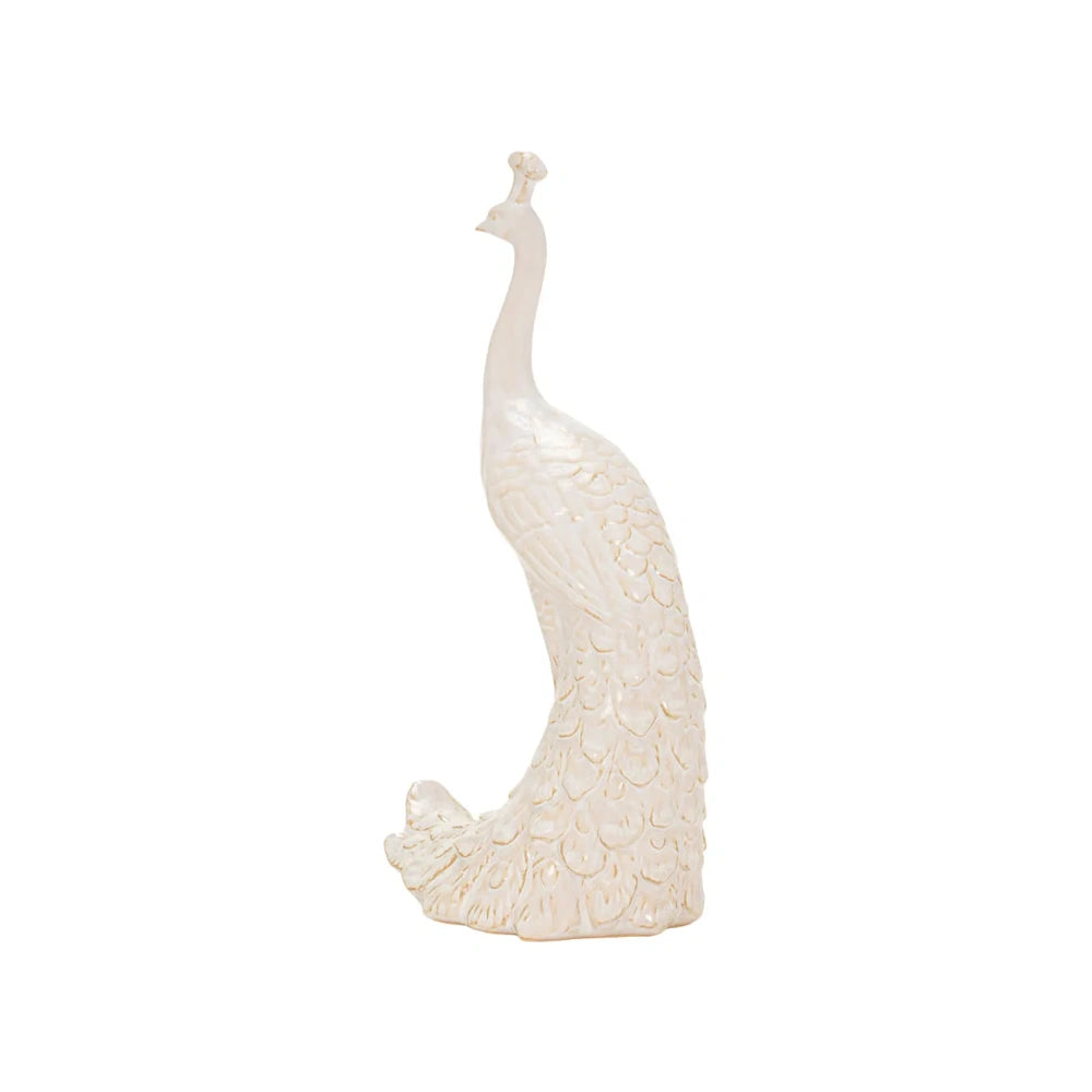 Profile view of an elegant, cream-colored peacock sculpture with textured feather details and a crest.