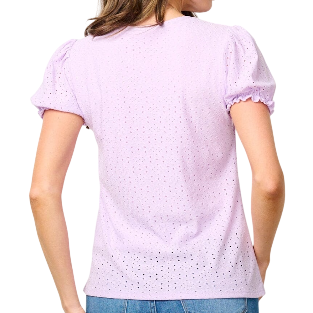 A woman from behind wearing a short-sleeved lavender eyelet blouse and blue jeans.