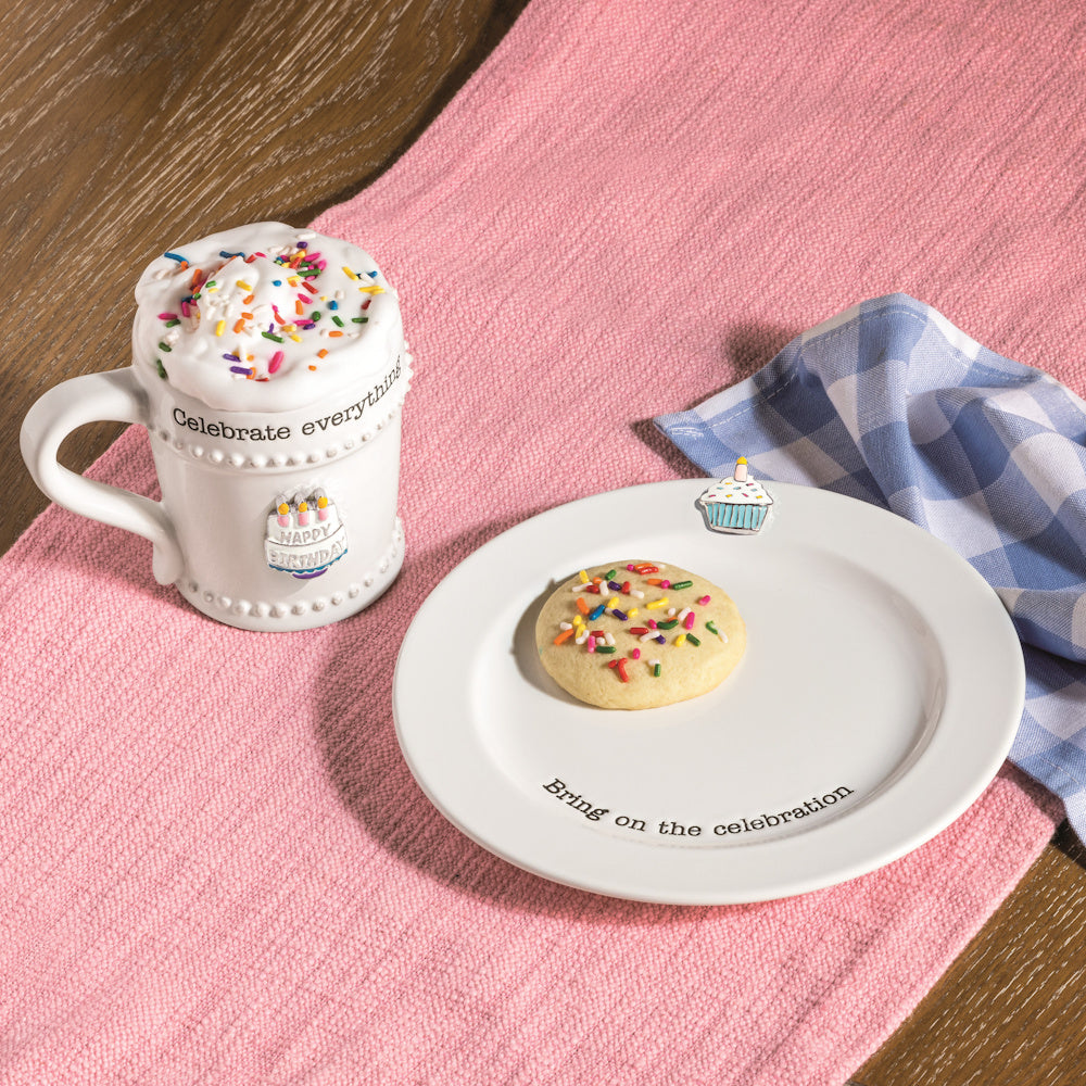 Birthday mug and matching plate with a sprinkle cookie on a pink runner, featuring "Celebrate everything" text.