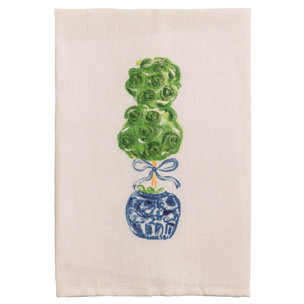 Green topiary in a blue and white chinoiserie pot with a blue bow on a white linen tea towel.