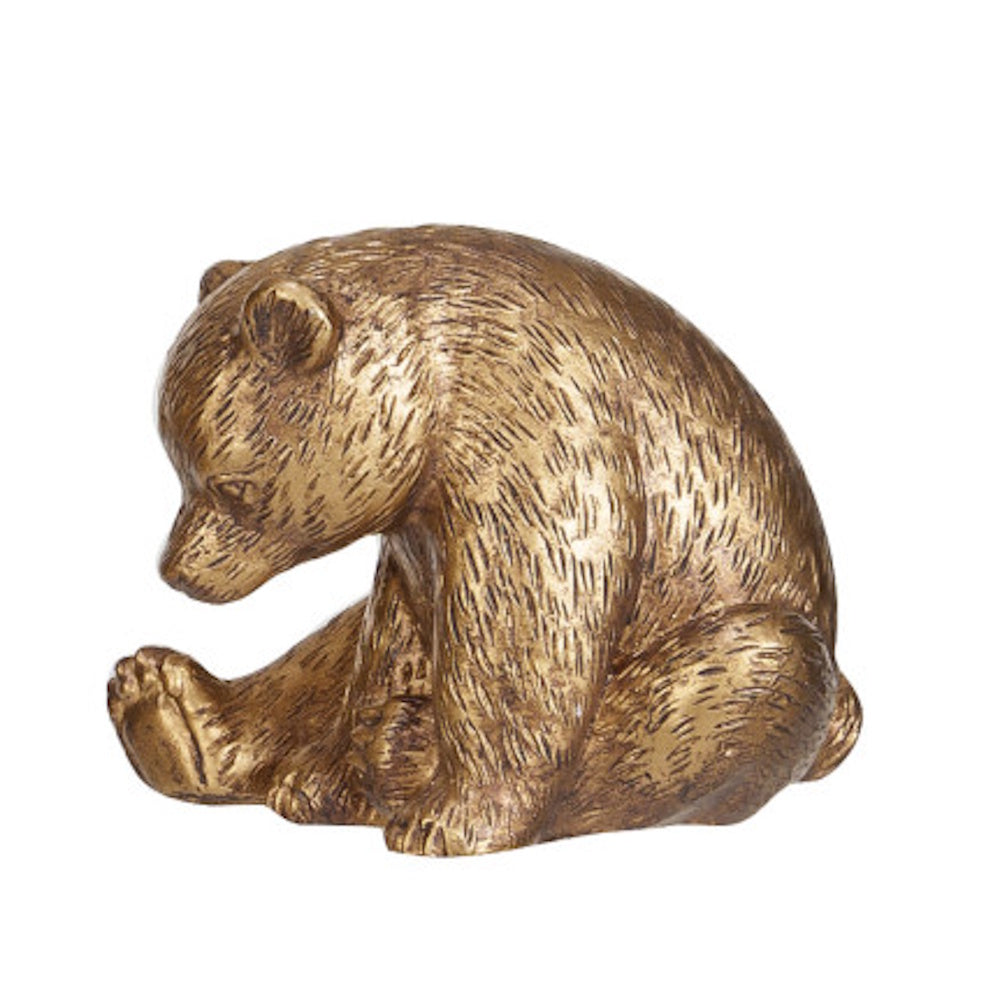 Golden bronze bear cub figurine sitting with its head lowered against a white background.