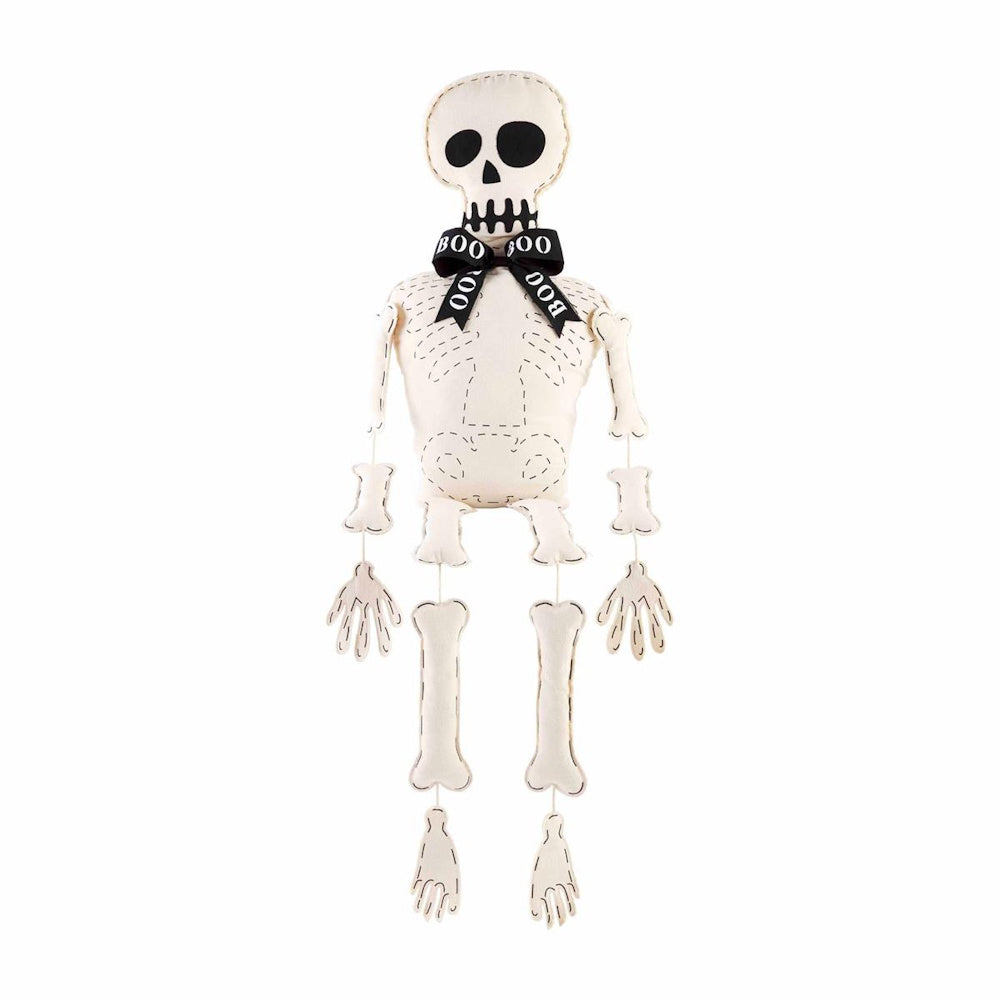 A fabric skeleton decoration with stitched details and a black bowtie that reads "BOO".
