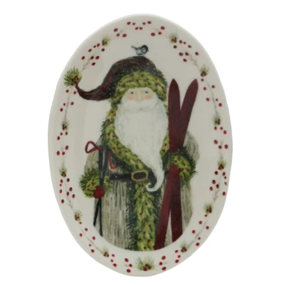 An oval white platter featuring Santa holding wooden skis and ski poles, with a small bird on his hat.