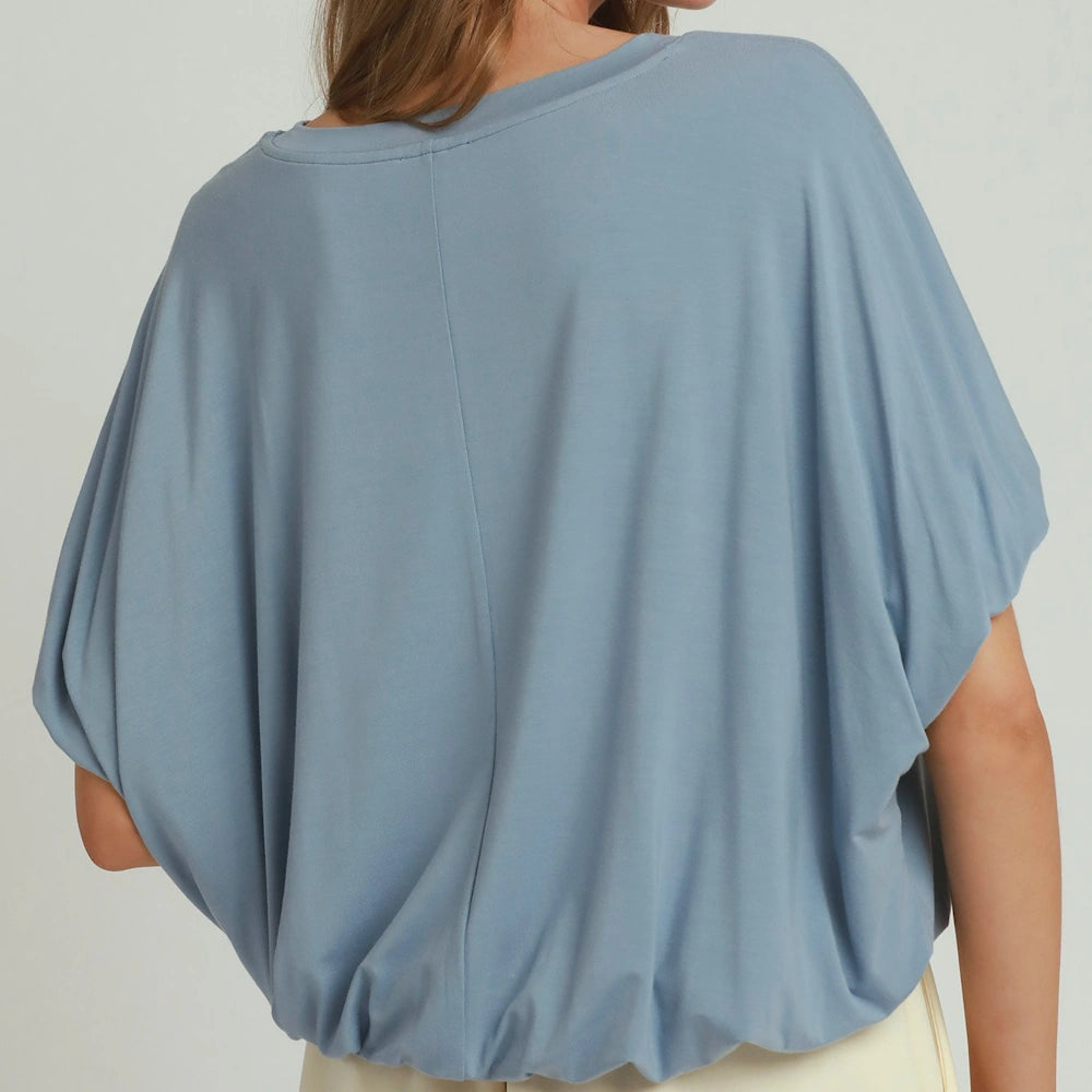 Back view of a slate blue short-sleeve top featuring relaxed, dolman-style sleeves and a gathered bubble hem.