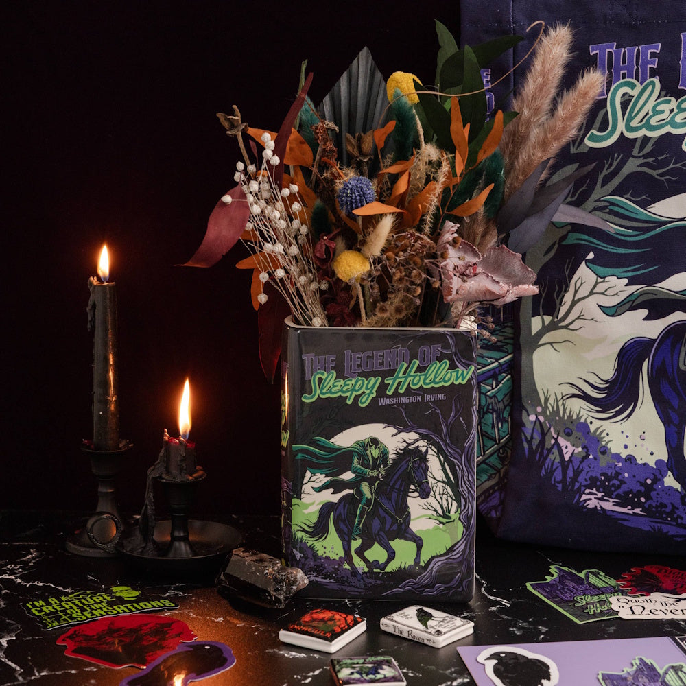 Book-shaped vase with "The Legend of Sleepy Hollow" cover art filled with dried flowers beside candles.