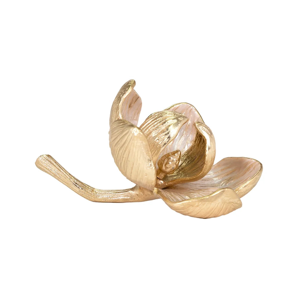 A small gold flower sculpture with light pink enamel on the inside of its open petals.