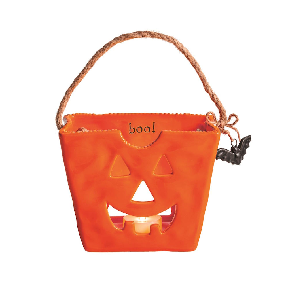 Orange ceramic jack-o'-lantern treat bag lantern with twine handle and lit tealight inside.