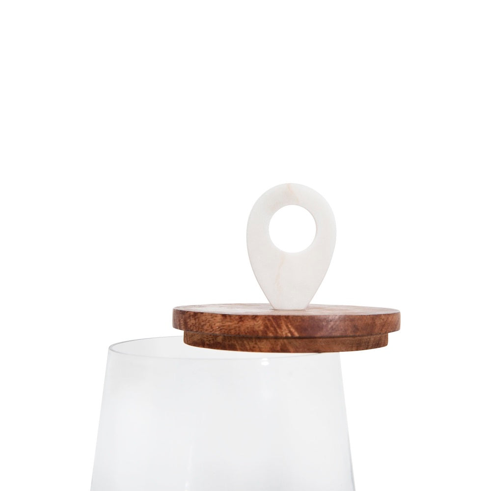 Open clear glass jar with its wooden lid and white marble ring handle resting slightly askew on top.