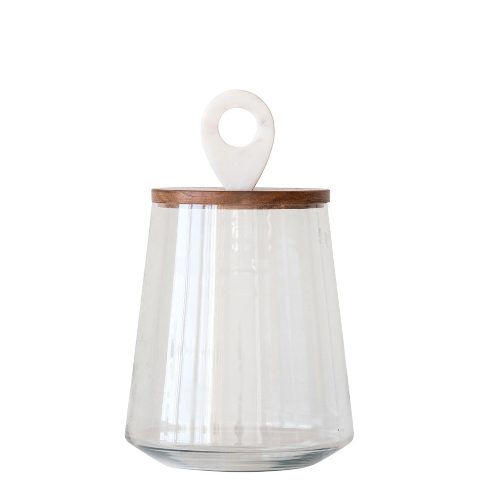 Clear, tapered glass jar with a flat wooden lid topped by a white marble ring handle against a white background.