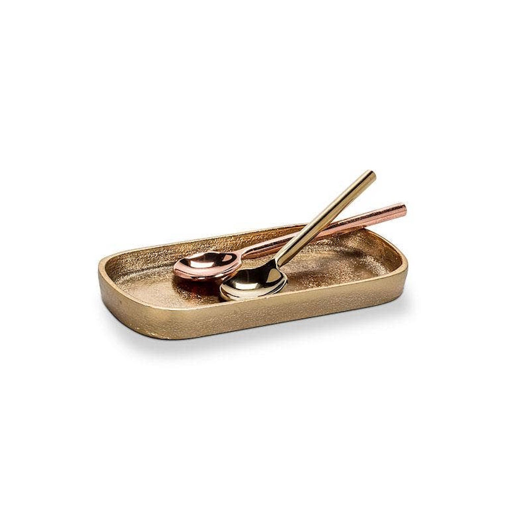 Small textured brass oval tray holding gold and copper spoons on a white background.