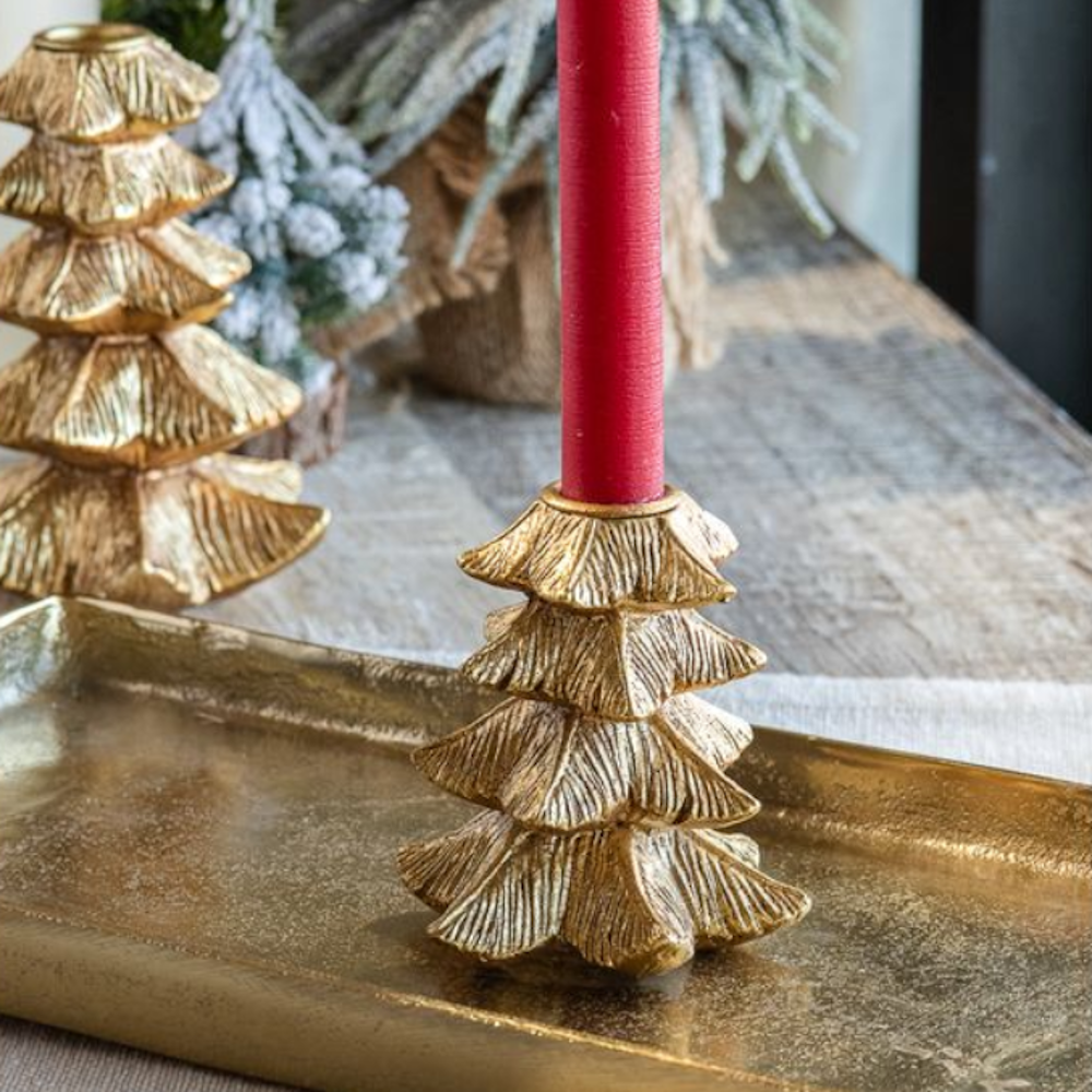 Gold tree-shaped taper candle holder with a red candle resting on a metallic tray.
