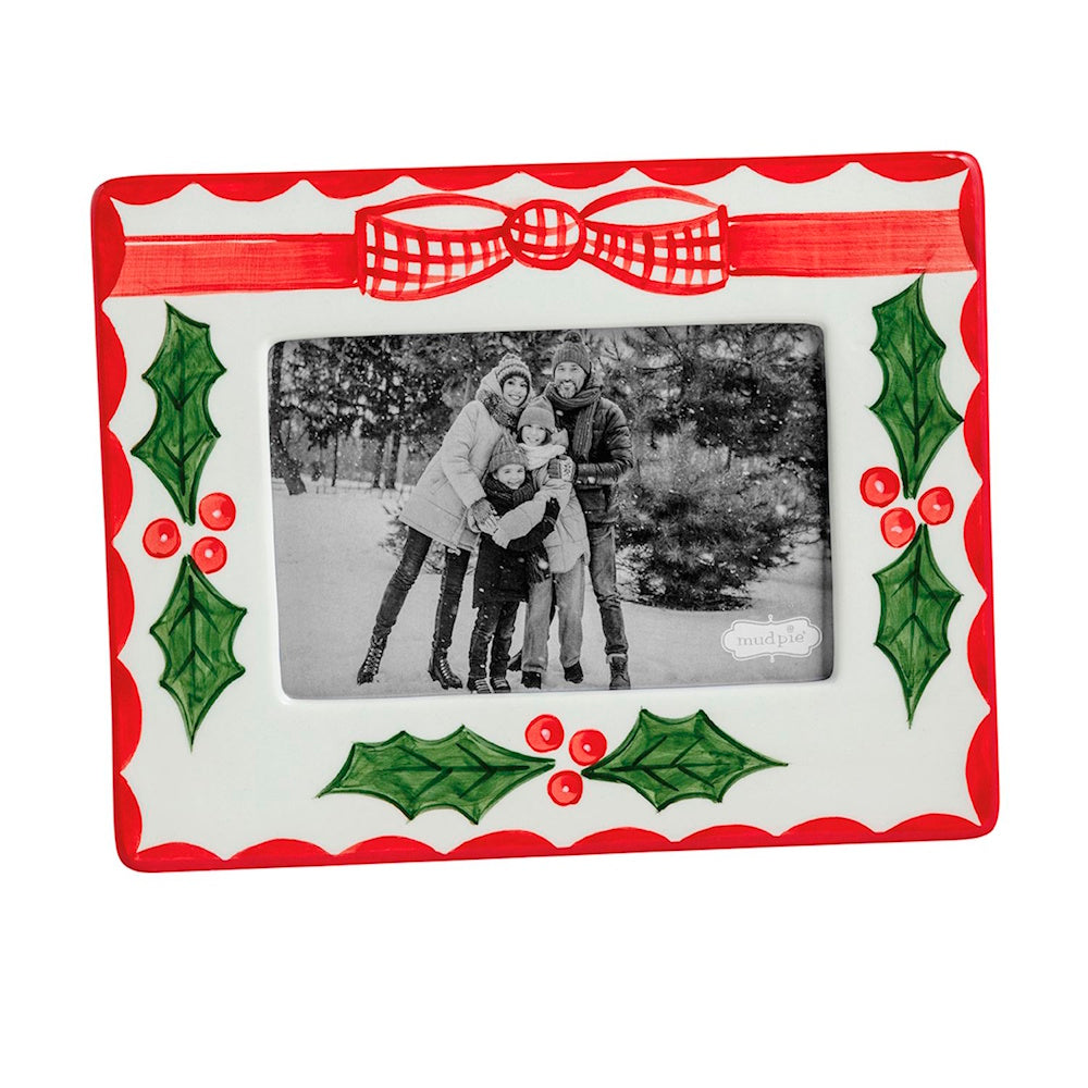 Hand-painted ceramic picture frame with holly leaves, red berries, and a plaid bow surrounding a photo.