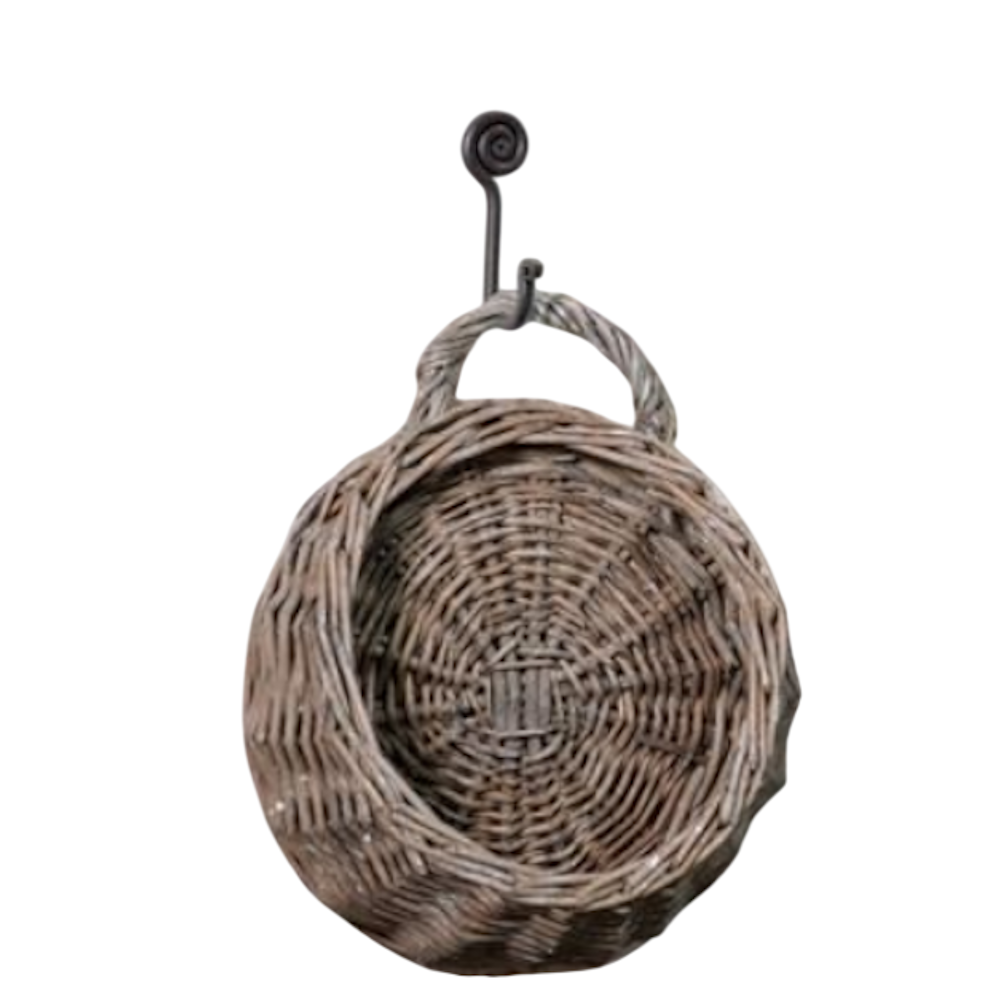 Small round woven willow wall pocket basket hanging from a dark metal hook against a white background.