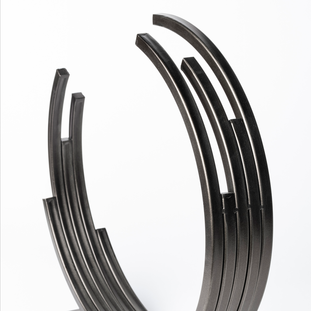 Close-up of a modern bronze Taj sculpture featuring tiered, concentric metal rings with a textured finish.