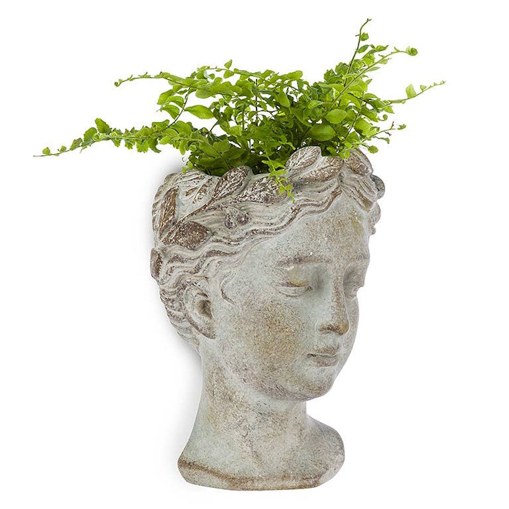 Classical stone-style female bust head planter holding green leafy fern plants.