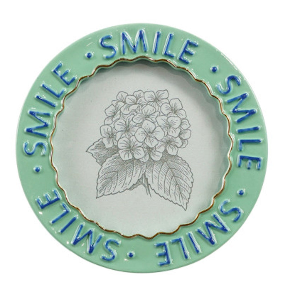 Round, light green frame with "SMILE" repeated in blue text, containing a sketch of a hydrangea.