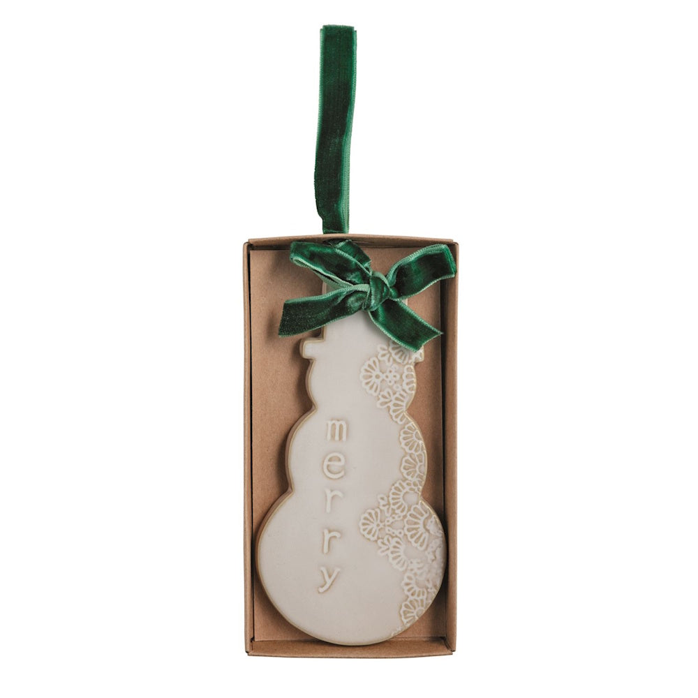 White snowman Christmas ornament with "merry" text and green velvet ribbon in a box.